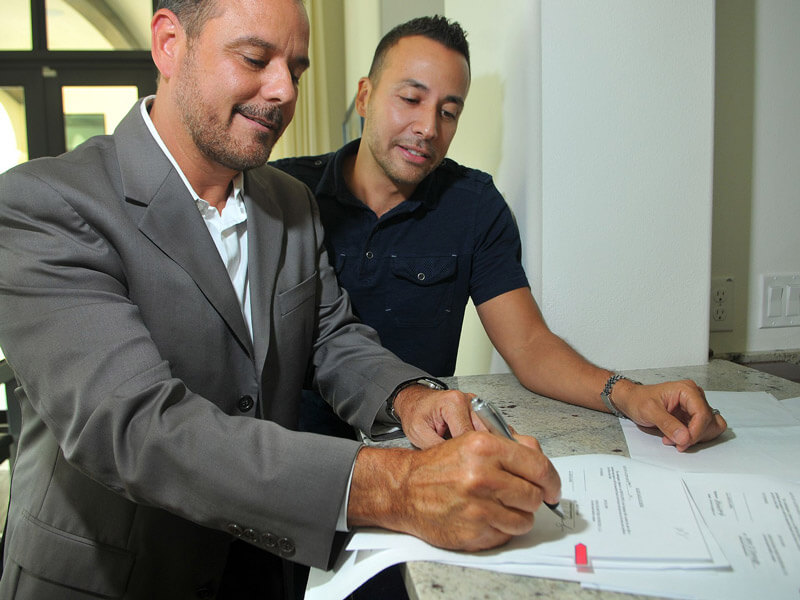 Condo Developers signing paperwork and smiling like they just made the happiest signature of their lives.